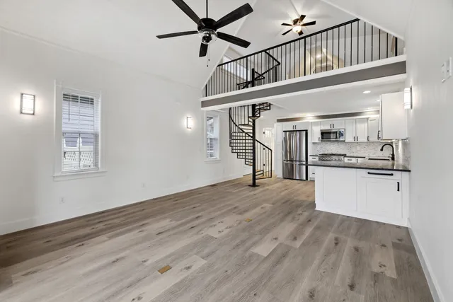 a view of empty room with wooden floor and kitchen view