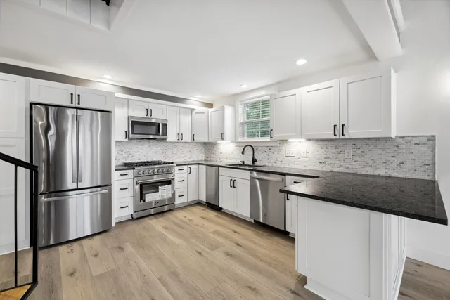 a kitchen with granite countertop a refrigerator oven a sink and white cabinets