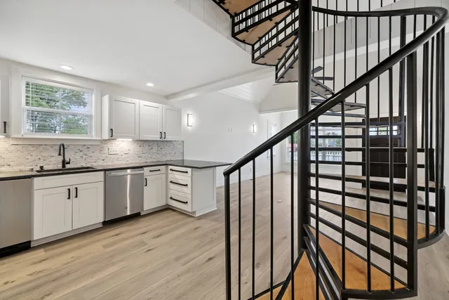 a kitchen with granite countertop white cabinets and wooden floor