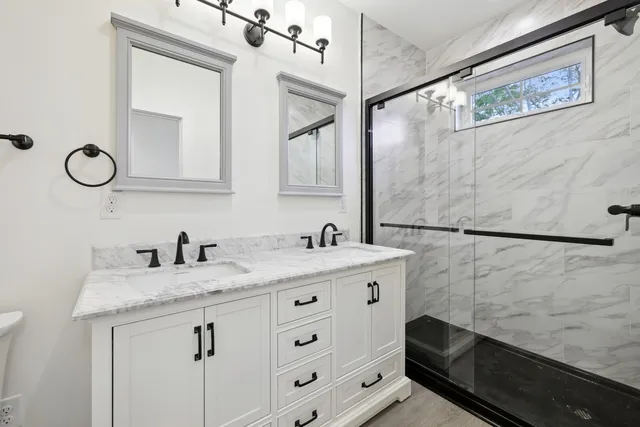 a bathroom with a granite countertop sink a mirror and a shower