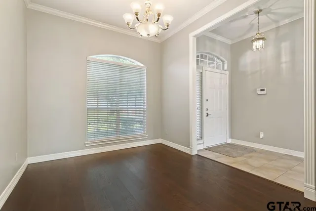 an empty room with wooden floor chandelier fan and windows