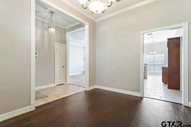 an empty room with wooden floor and a kitchen space