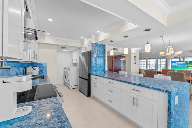 a kitchen with stainless steel appliances kitchen island granite countertop a refrigerator and a sink