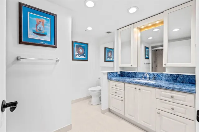 a bathroom with a granite countertop toilet a sink and a mirror