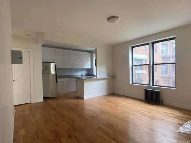 a view of empty room with wooden floor and windows