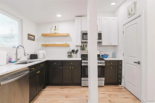 a kitchen with stainless steel appliances granite countertop a refrigerator a sink dishwasher a stove and white countertops with wooden floor