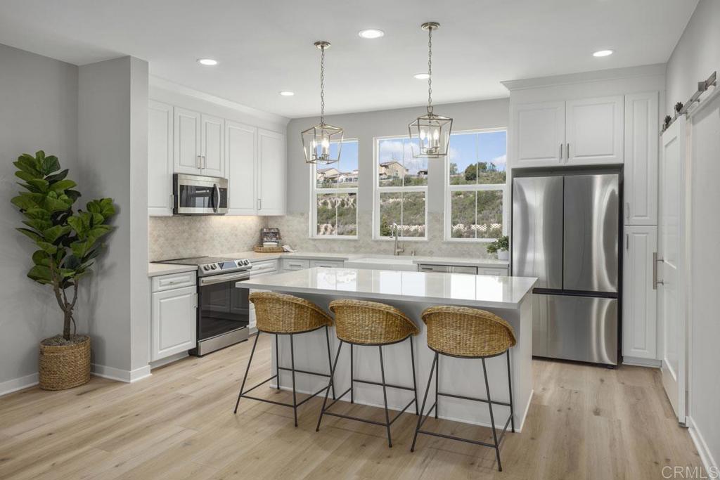 2535 Chamomile Lane Carlsbad, CA 92008 - Photo 1 of 15 a kitchen with stainless steel appliances granite countertop a refrigerator a stove a sink dishwasher and a dining table with wooden floor