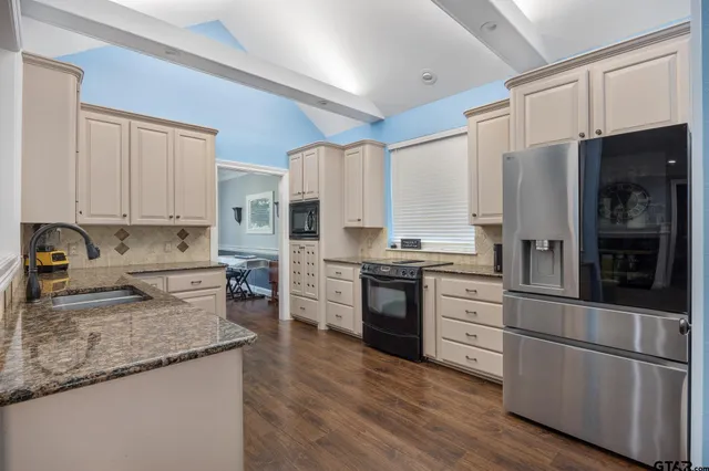 a kitchen with stainless steel appliances granite countertop a refrigerator a stove and a sink