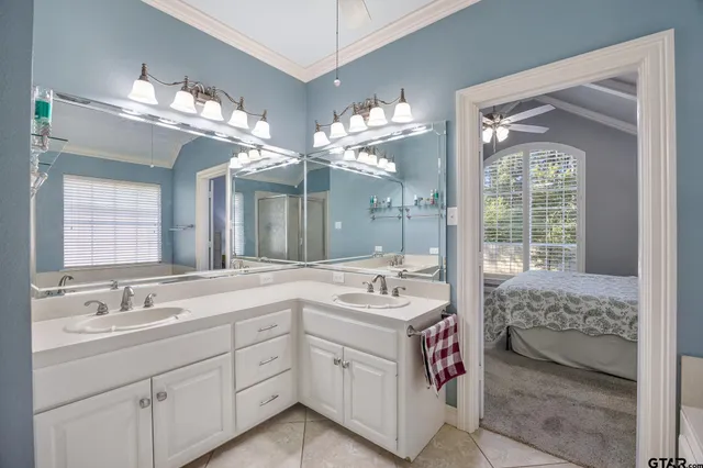 a spacious en suite bathroom with double vanity a sink a large mirror and a bathtub