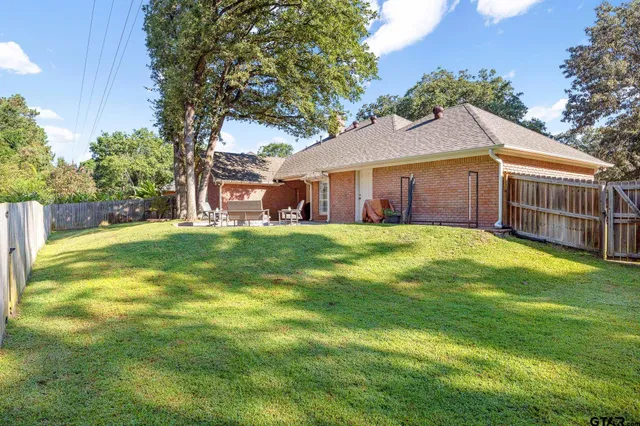 a view of a brick house with a big yard and large trees