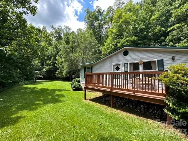 a view of house with a yard and deck