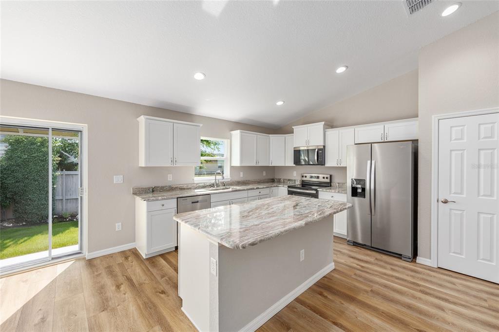 17654 Southwest 112th Lane Dunnellon, FL 34432 - Photo 6 of 17 a kitchen with stainless steel appliances granite countertop a stove top oven a refrigerator a sink and dishwasher with white cabinets