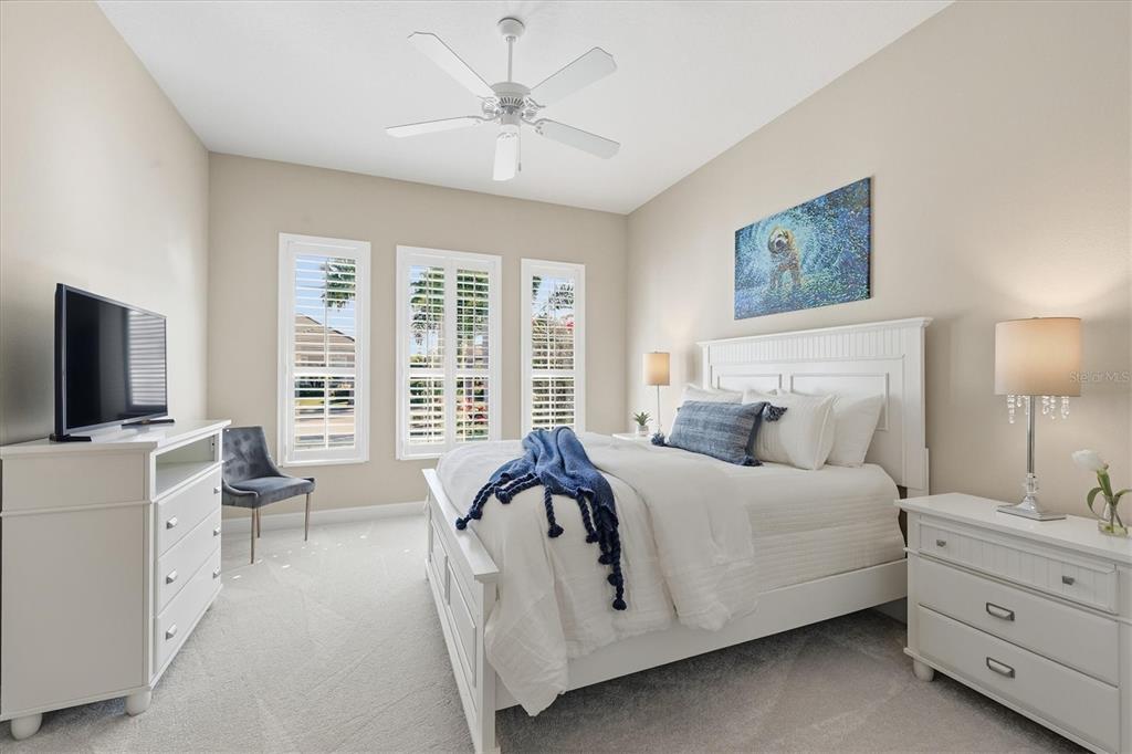 15909 Castle Park Terrace Lakewood Ranch, FL 34202 - Photo 26 of 66 a spacious bedroom with a bed a couch and a flat tv screen