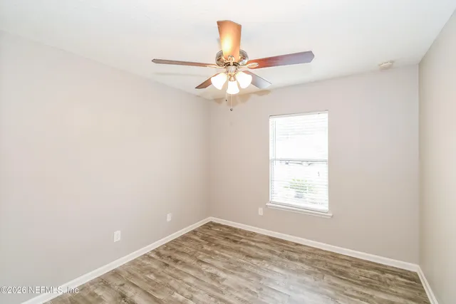 an empty room with windows and fan