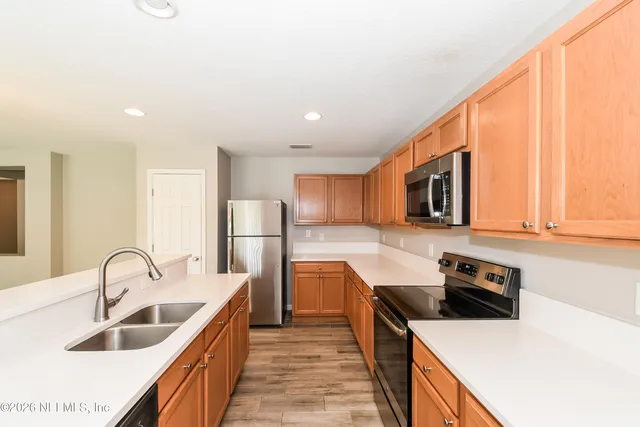 a kitchen with stainless steel appliances a sink a stove a refrigerator cabinets and a window