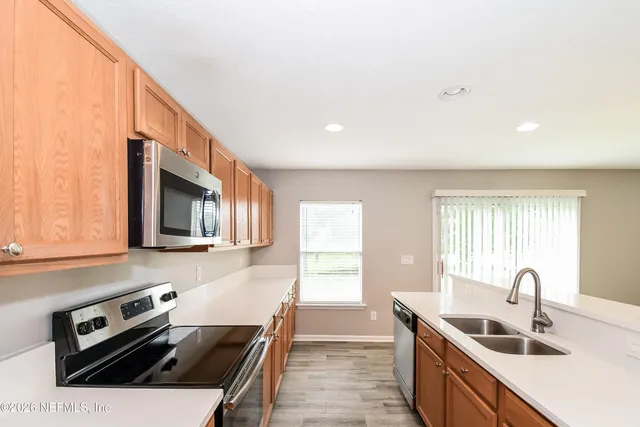 a kitchen with stainless steel appliances a sink a stove a microwave a sink a refrigerator and cabinets