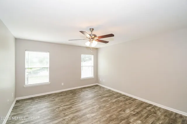 an empty room with a window and a ceiling fan