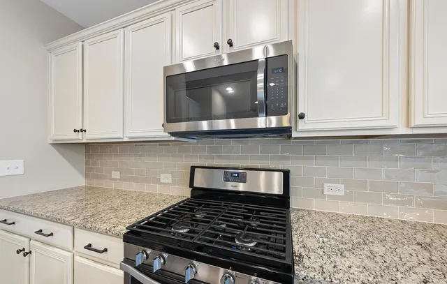 a kitchen with granite countertop white cabinets and stainless steel appliances