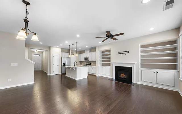 a living room with stainless steel appliances furniture a fireplace and wooden floor