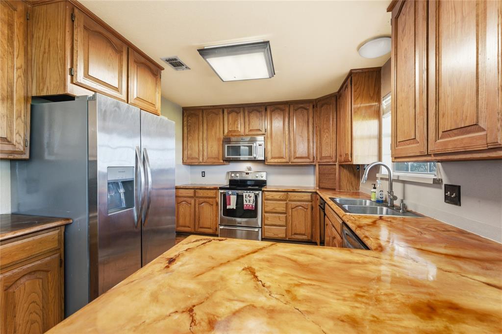14529 County Road 511 Venus, TX 76084 - Photo 2 of 33 Kitchen with wood finish cabinets, stainless steel appliances, and light stone countertops