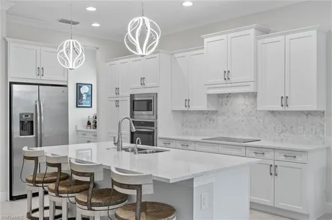 a kitchen with stainless steel appliances kitchen island granite countertop a table chairs and a refrigerator