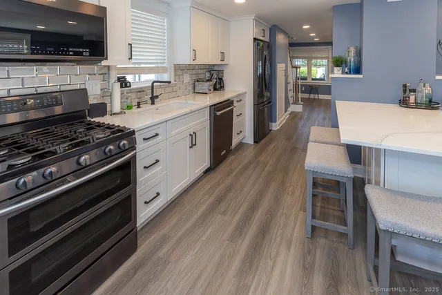 a large kitchen with wooden floor a stove and a sink