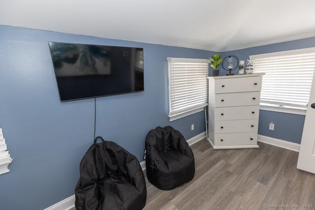 a living room with a bed and a flat tv screen on dresser