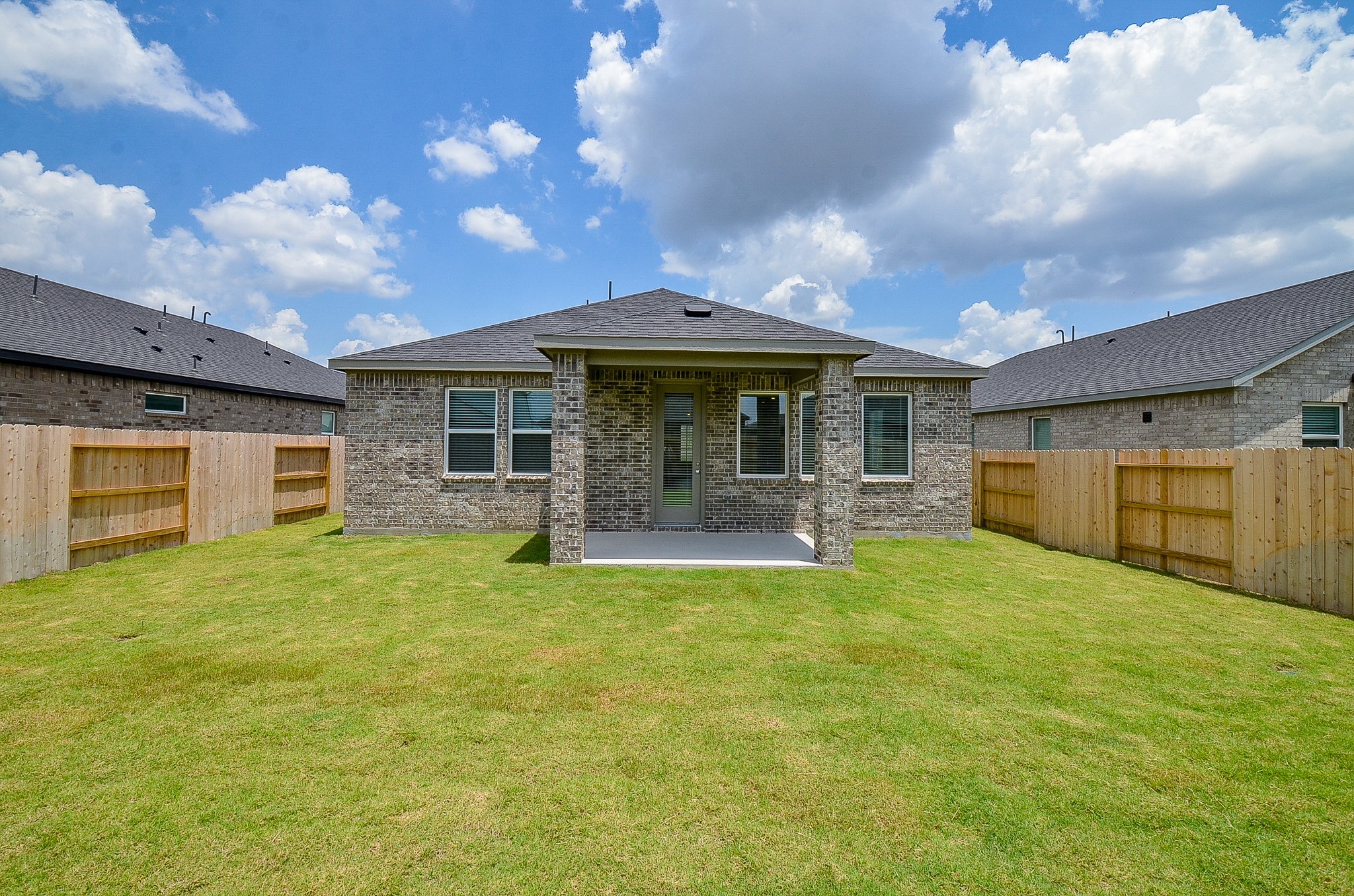 9727 Rialto Hts Drive Cypress, TX 77433 - Photo 34 of 37 This photo showcases a covered patio with brick pillars overlooking a fenced backyard. The area features a concrete floor and is surrounded by a wooden privacy fence, making it ideal for outdoor relaxation.