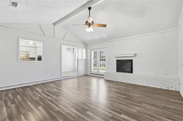 a view of an empty room with wooden floor fireplace and a window