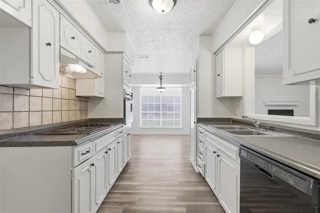 a kitchen with granite countertop a sink stove and cabinets
