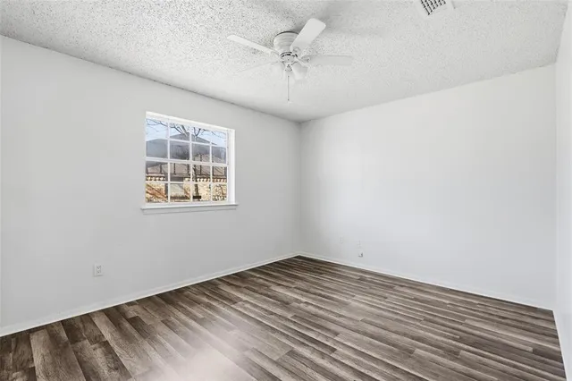 an empty room with a chandelier fan and windows