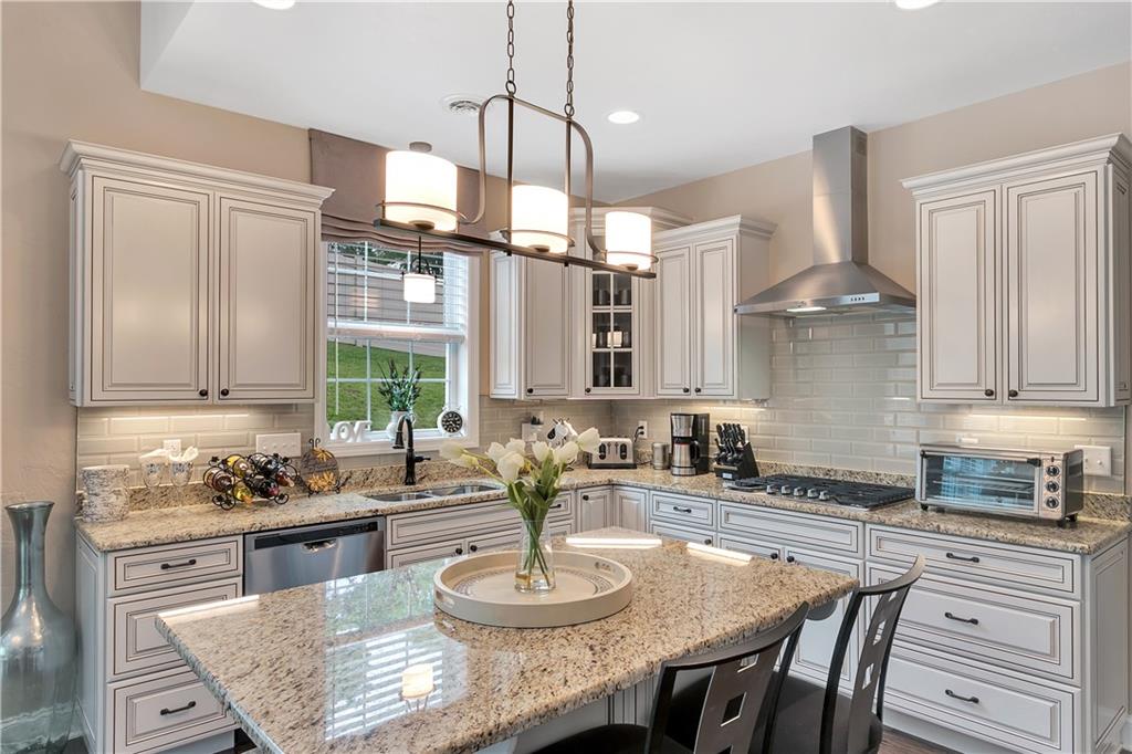100 Meadow Road Irwin, PA 15642 - Photo 8 of 25 GORGEOUS Granite Topped Island/Counters, Subway Tile Backsplash and Stainless Vent Hood Over Gas Cooktop.