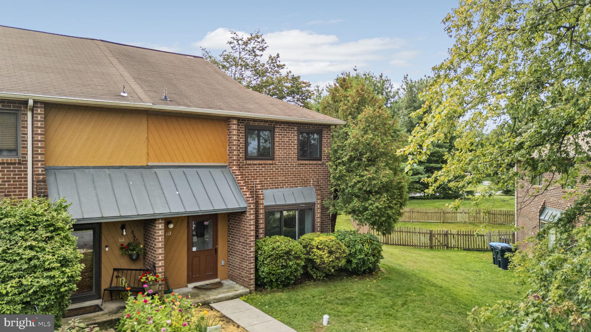 a view of a house with brick walls plants and large tree