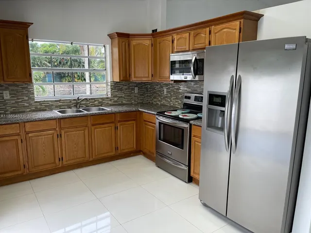 a kitchen with stainless steel appliances granite countertop a refrigerator and a sink