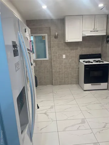 a kitchen with granite countertop a refrigerator a stove a washer and dryer