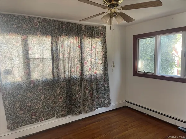 an empty room with wooden floor fan and windows