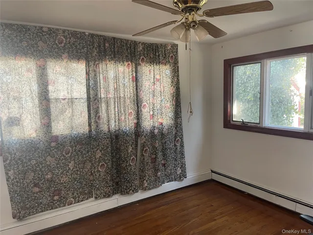 an empty room with wooden floor fan and windows