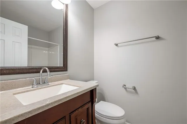 a bathroom with a granite countertop sink a toilet and a mirror