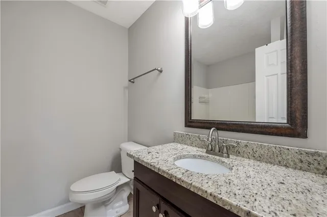 a bathroom with a granite countertop sink a toilet and a mirror