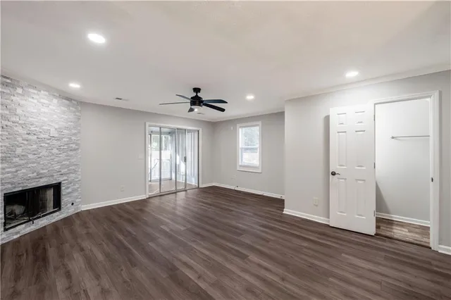 a view of an empty room with wooden floor fireplace and a window