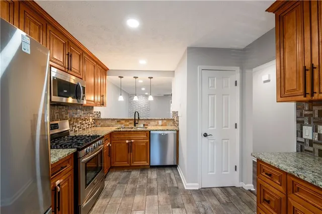 a kitchen with stainless steel appliances granite countertop a stove a sink and a refrigerator