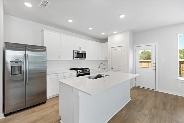 a kitchen with stainless steel appliances granite countertop a sink a stove a refrigerator and cabinets