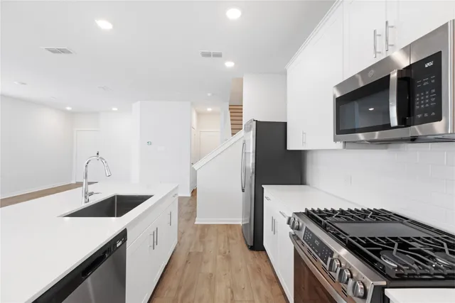 a kitchen with stainless steel appliances granite countertop a sink and a stove top oven with wooden floor