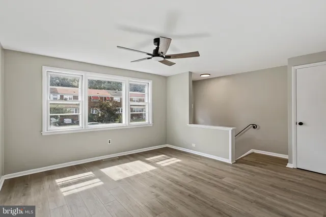 a view of empty room with wooden floor and fan