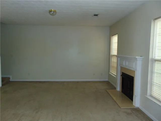 an empty room with a fireplace and windows