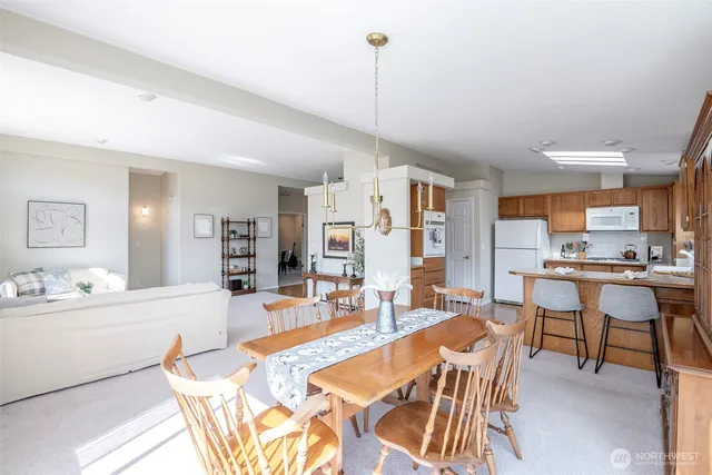 a kitchen with a refrigerator a stove and a dining table with wooden floor