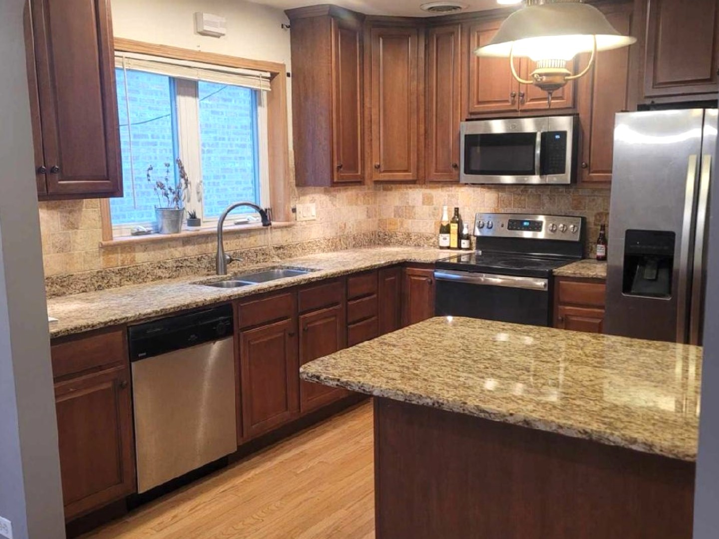 4144 North Parkside Avenue, Unit 1 Chicago, IL 60634 - Photo 2 of 3 a kitchen with stainless steel appliances granite countertop a sink stove microwave refrigerator and wooden cabinets