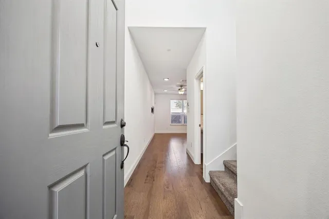 a view of a hallway with wooden floor and staircase