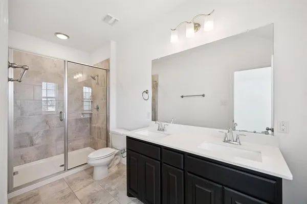 a bathroom with a double vanity sink toilet and shower