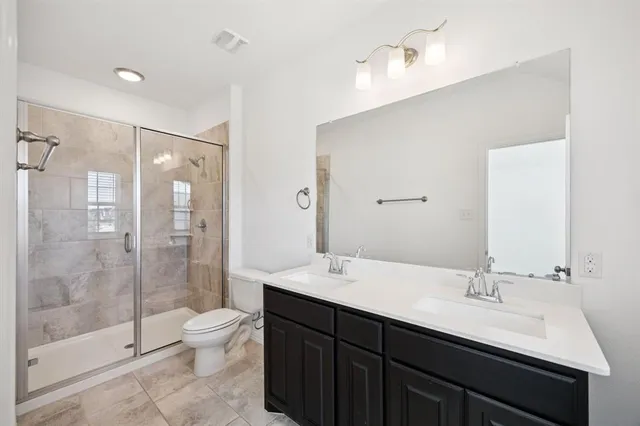 a bathroom with a double vanity sink toilet and shower